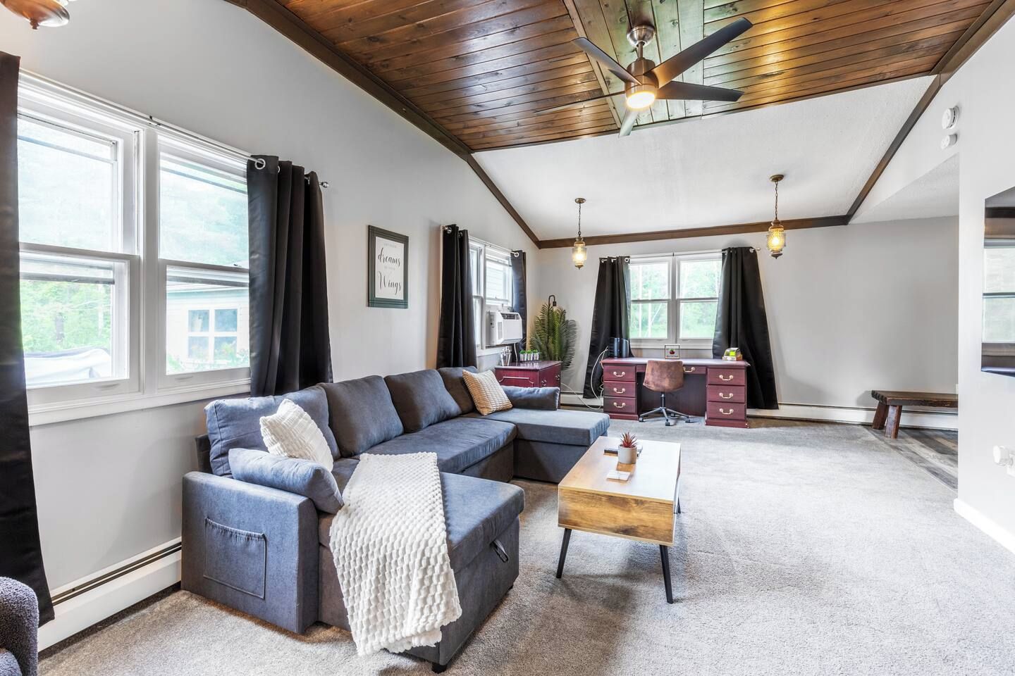 A modern living room with a sectional sofa, a coffee table, and a desk area.