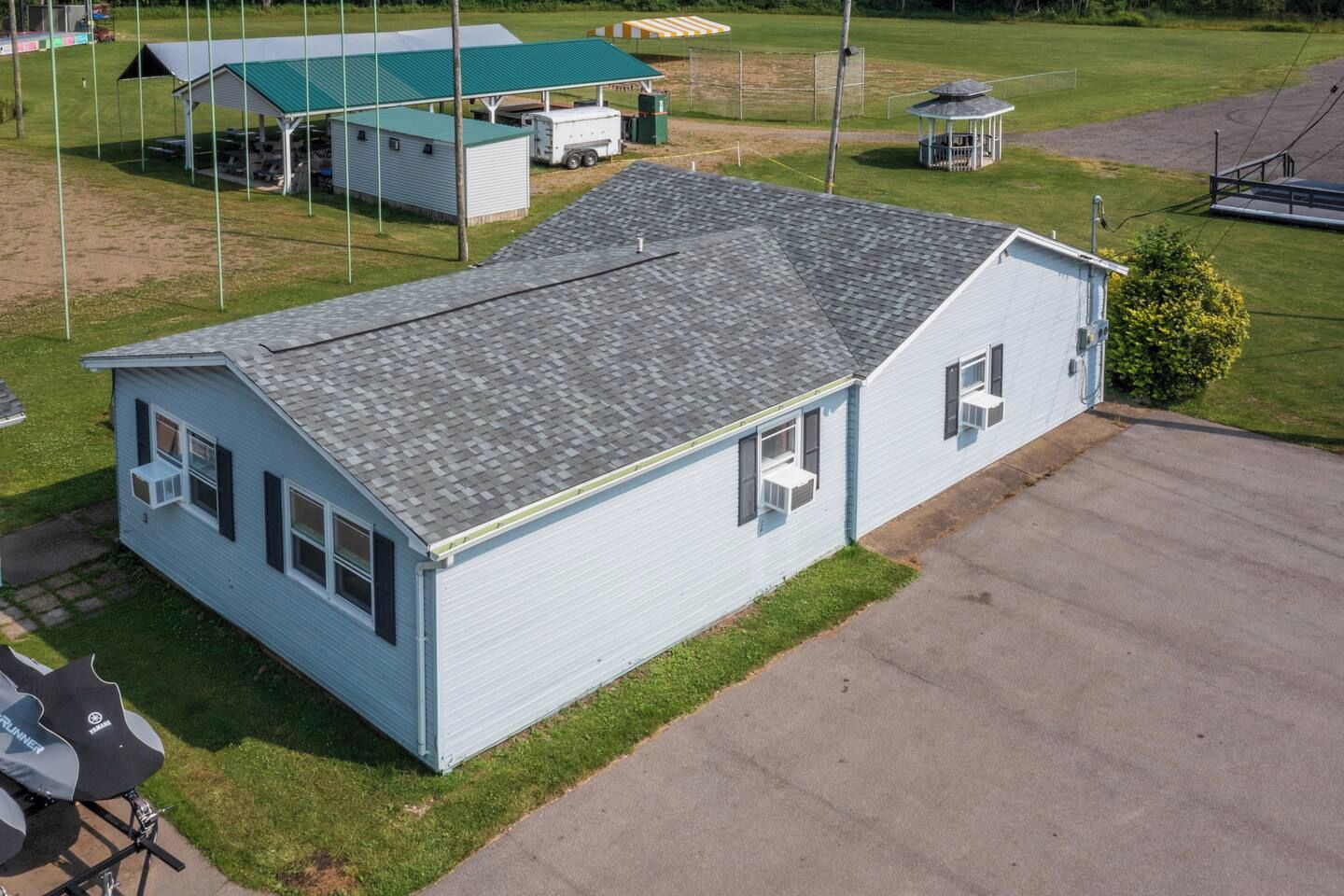 A single-story building with a sloped roof, a covered porch, and a small adjacent structure.