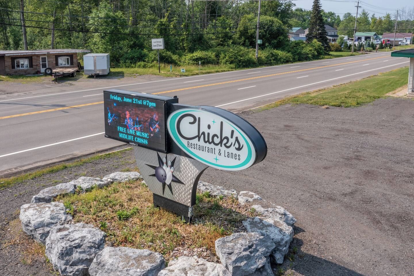 A roadside sign for Chick's Restaurant & Lanes with a live music event advertisement.