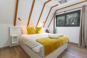 A bedroom with a bed, a bedside table, a window with curtains, and wooden beams on the ceiling. - Star Lodge by Atlantic Holiday (São Vicente)