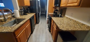 A kitchen with granite countertops, wooden cabinets, a stainless steel sink, and a dishwasher. - North Pole Getaway + 2 bd Home w/ Double Garage (Fairbanks)