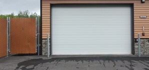 A closed garage door with a metal fence and a stone wall. - North Pole Getaway + 2 bd Home w/ Double Garage (Fairbanks)