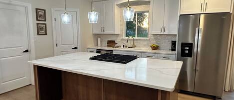 A modern kitchen with a central island, stainless steel appliances, and pendant lighting.