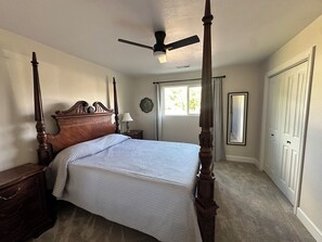 A bedroom with a four-poster bed, a ceiling fan, a window with curtains, a bedside table with a lamp, and a door. - 3-bedroom newly remodeled house in perfect Flora Vista (Flora Vista)
