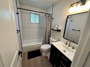 A bathroom with a white bathtub, a toilet, a vanity with a mirror, and a shower curtain. - 3-bedroom newly remodeled house in perfect Flora Vista (Flora Vista)
