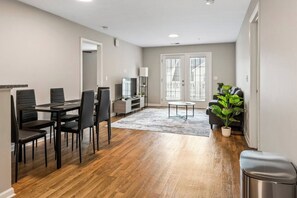 Un salon moderne avec un coin repas, un plancher en bois et une grande plante en pot.