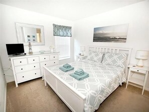 A bedroom with a bed, a dresser, a television, a window with blinds, and a wall-mounted picture. - Wooded Views 4 BD/3 BA/Terra Verde Resort - 217 HB (Kissimmee)