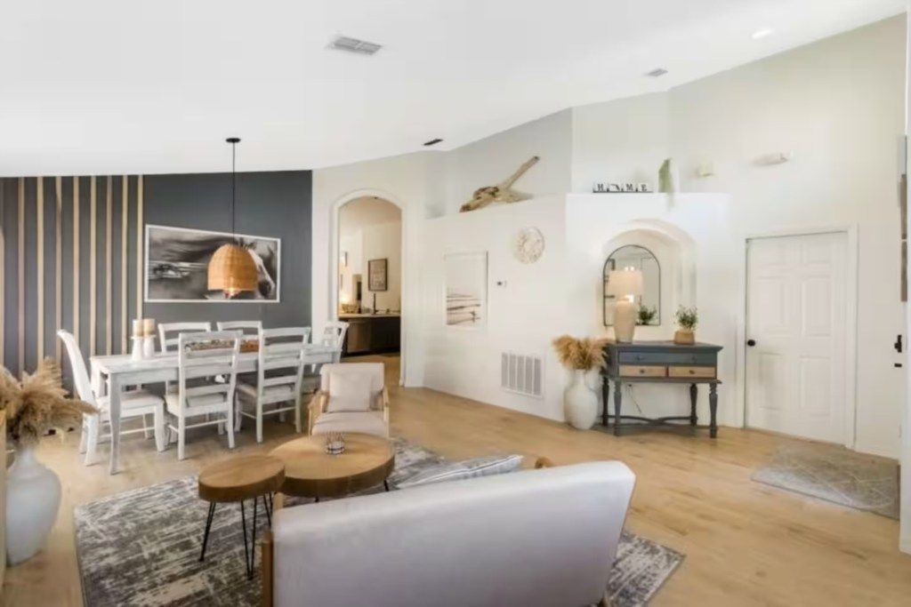 A modern living room with a dining area, a fireplace, and a staircase leading to another level.