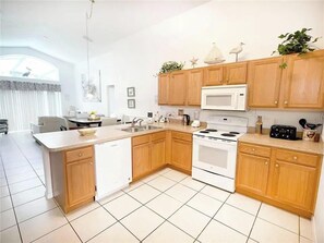 A modern kitchen with wooden cabinets, a white stove, and a microwave. - Wooded Views 4 BD/3 BA/Terra Verde Resort - 217 HB (Kissimmee)