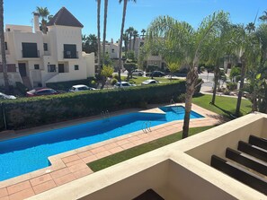 A swimming pool with a clear blue water, surrounded by a paved deck and a small grassy area. - Sunny Spanish Escape – 2-Bed Townhouse with Stunning Pool Views (San Javier)