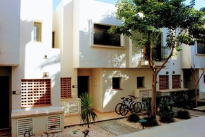 A residential building with multiple balconies, a bicycle parked outside, and a small garden area. - Sunny Spanish Escape – 2-Bed Townhouse with Stunning Pool Views (San Javier)