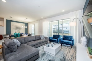A modern living room with a grey sofa, blue armchairs, and a white coffee table. - 8 BD/ 5 BA/ Sonoma Resort - 2614 CA (Kissimmee)