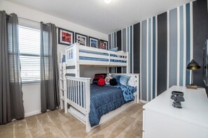 Ein Kinderzimmer mit Etagenbett, Schreibtisch und Lampe.