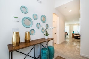 A hallway with a wooden console table, teal decorative mirrors, and a potted plant. - 8 BD/ 5 BA/ Sonoma Resort - 2614 CA (Kissimmee)