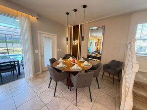A dining area with a round table set for six, surrounded by six chairs. There is a large mirror on the wall, a ceiling light fixture, and a door leading to another room. - Corner-Lot 5 BD/ 4.5 BA/ Windsor Island - 1000 PD (Davenport)