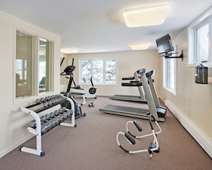 A home gym with treadmills, a stationary bike, dumbbells, and a TV. - 2BR/2BA Suite at Smugglers' Notch · Three Mountains · Heated Pool (Jeffersonville)