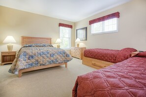 Ein Schlafzimmer mit einem großen Bett, zwei Nachttischen, einer Kommode und zwei Fenstern mit Vorhängen.