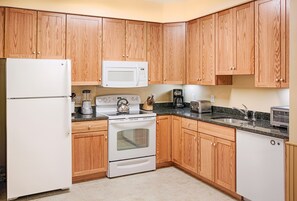 A kitchen with wooden cabinets, a refrigerator, a microwave, a stove, and a toaster. - 2BR/2BA Suite at Smugglers' Notch · Three Mountains · Heated Pool (Jeffersonville)
