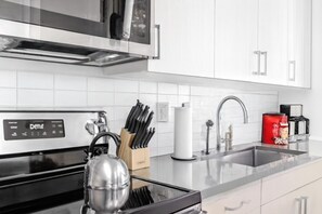 A modern kitchen with a built-in oven, a kettle, and a knife block. - Stylish Studio | Skyline Views + Pool 30 (Birmingham)