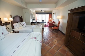 Ein Hotelzimmer mit zwei Betten, einem Fernseher, einem Schreibtisch und einem Stuhl.