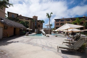 A resort pool area with lounge chairs, umbrellas, and a water slide. - Jr Suite at The Club at Hacienda del Mar (Cabo San Lucas)