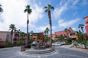 A courtyard with palm trees, a fountain, and a parking area with cars. - Jr Suite at The Club at Hacienda del Mar (Cabo San Lucas)