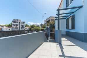 Ein Wohngebäude mit Balkon und Treppe vor blauem Himmel.