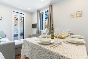 A dining area with a table set for four, a bottle of wine, and a television on the wall. - Chez Agostinha by Atlantic Holiday (Funchal)
