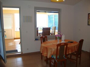 A dining area with a table set for four, a window with a view of the outside, and a door leading to another room. - Superior One Bedroom Apartment with Balcony and Sea View (Petrcane)