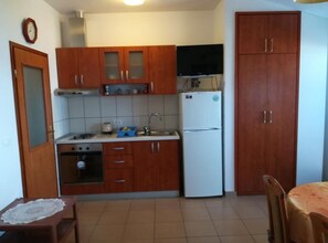 A compact kitchen with wooden cabinets, a refrigerator, a stove, and a sink. - Superior One Bedroom Apartment with Balcony and Sea View (Petrcane)