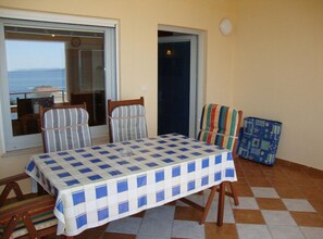 A balcony with a checkered tablecloth, striped chairs, and a suitcase. - Superior One Bedroom Apartment with Balcony and Sea View (Petrcane)