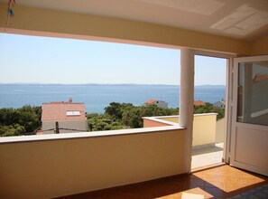 Un balcón con vistas al mar y montañas lejanas.