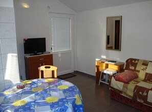 A bedroom with a bed, a desk, a chair, a television, and a window with blinds. - One Bedroom Apartment with Terrace and Garden (Petrcane)