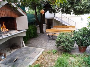 A backyard with a barbecue grill, a wooden bench, a potted plant, and a staircase leading to an upper level. - One Bedroom Apartment with Terrace and Garden (Petrcane)