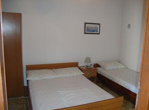 A bedroom with a large bed, two smaller beds, a nightstand with a lamp, and a framed picture on the wall. - One Bedroom Apartment with Terrace and Sea View (Petrcane)