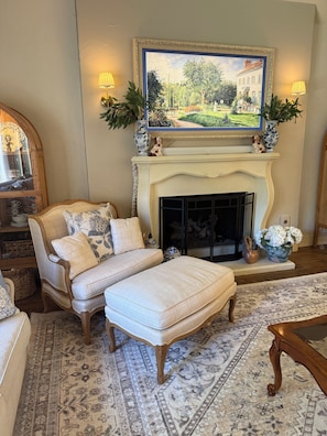 A traditional living room with a fireplace, a sofa, an ottoman, and a patterned rug. - Lovely 4-bedroom house with AC in pleasant Tulsa neighborhood (Tulsa)