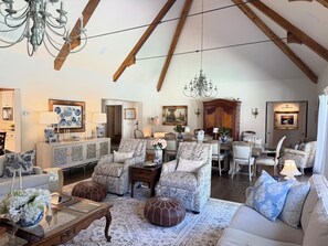 A spacious living room with high ceilings, a chandelier, and a dining area with a wooden table and chairs. - Lovely 4-bedroom house with AC in pleasant Tulsa neighborhood (Tulsa)
