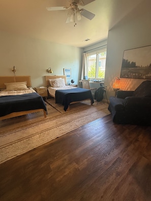 A bedroom with two beds, a desk, a chair, a ceiling fan, and a window with curtains. - Lovely 4-bedroom house with AC in pleasant Tulsa neighborhood (Tulsa)