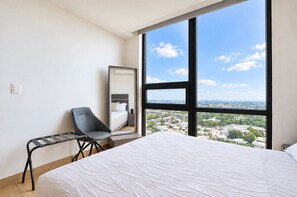 Een hotelkamer met een groot raam, een bed, een stoel en een spiegel.
