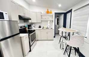 Een moderne keuken met roestvrijstalen apparatuur, witte kasten en een eetgedeelte met rieten stoelen.