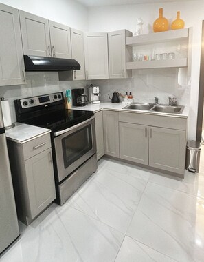 A modern kitchen with stainless steel appliances, white cabinetry, and a tiled floor. - Private studio by Miami International Airport (Miami)