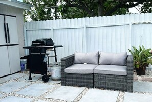 An outdoor patio area with a wicker sofa, a grill, and a potted plant. - Private studio by Miami International Airport (Miami)