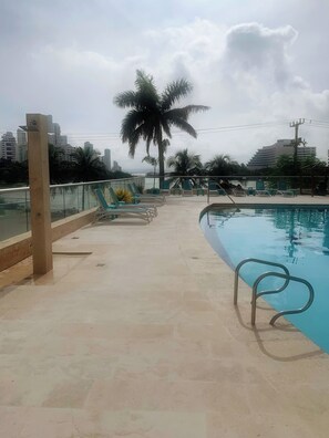 A swimming pool with a metal ladder, lounge chairs, and a palm tree. - 8b4 en El Laguito: cerca del mar, piscina y wifi (Cartagena de Indias)