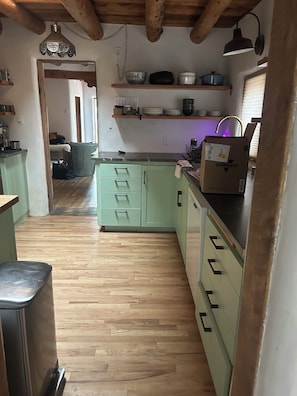 A kitchen with wooden flooring, green cabinets, and a wooden ceiling. - Lovely 2-bedroom house in tranquil Taos. (Taos)