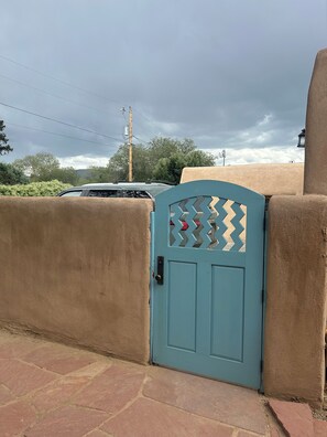 A turquoise gate with a chevron pattern, a beige wall, and a parked car. - Lovely 2-bedroom house in tranquil Taos. (Taos)