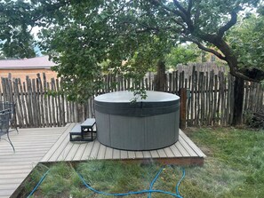 Un jacuzzi en una terraza de madera con una valla de madera al fondo.