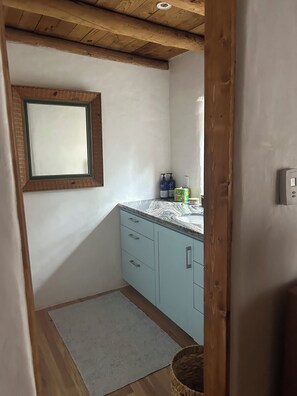 A bathroom with a wooden ceiling, a mirror, a sink, and a small window. - Lovely 2-bedroom house in tranquil Taos. (Taos)