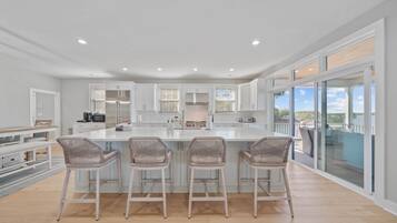 Una cocina moderna con una isla central, taburetes de bar y vistas al exterior.