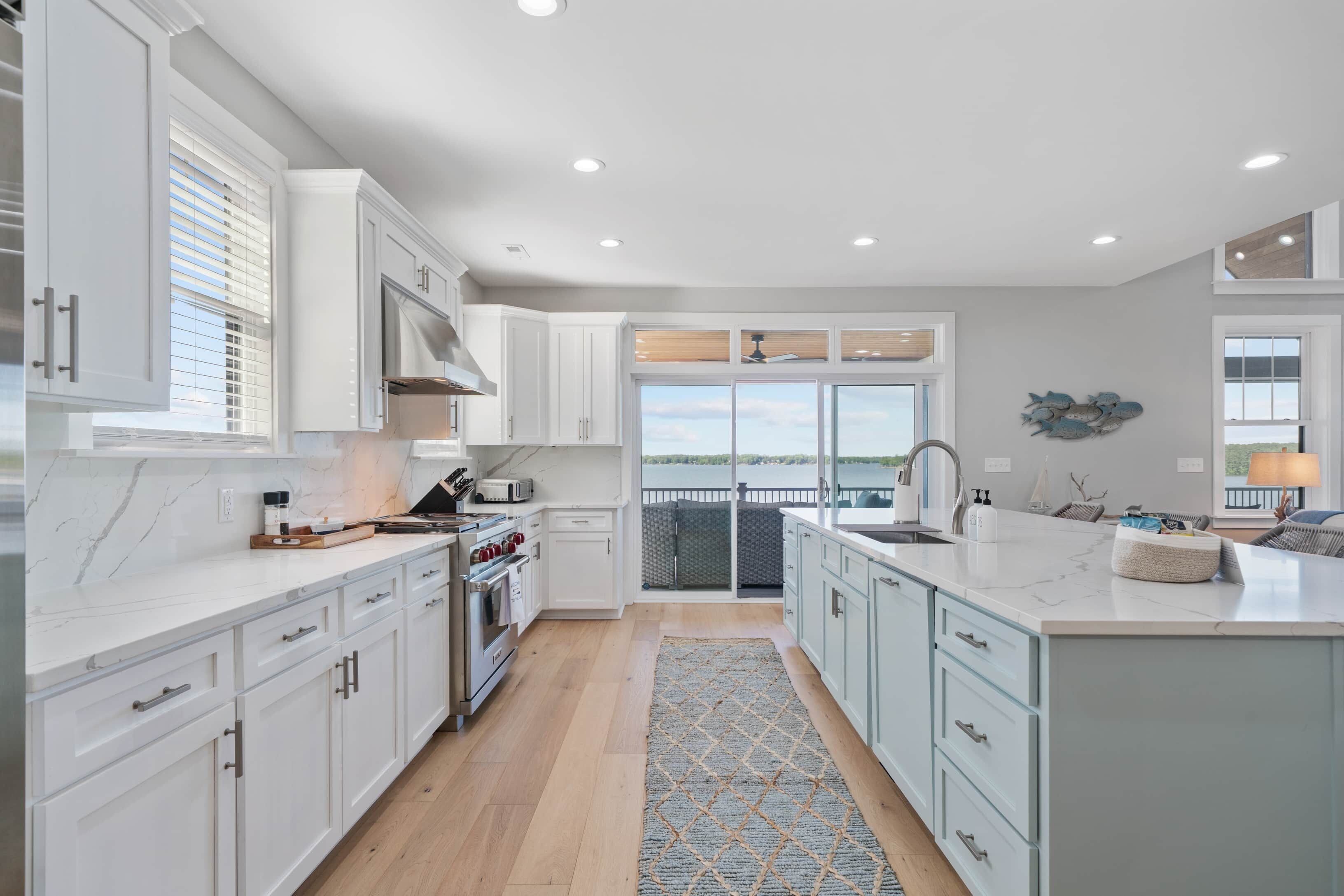 Una cocina moderna con armarios blancos, una isla grande y vistas al exterior.