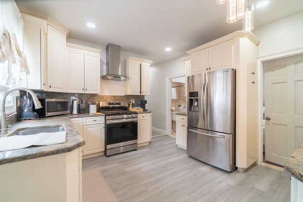 A modern kitchen with white cabinetry, stainless steel appliances, and a granite countertop.